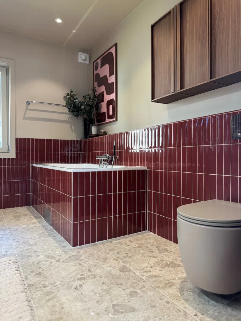 Badrumsrenovering i Bromma med rött kakel, badkar och toalett