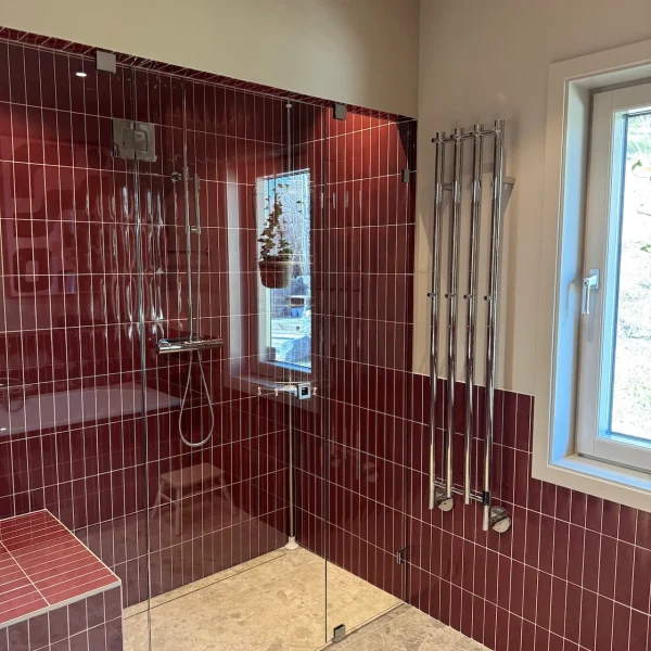 Badrumsrenovering i Stockholm med rött kakel i duschen med en handdukstork