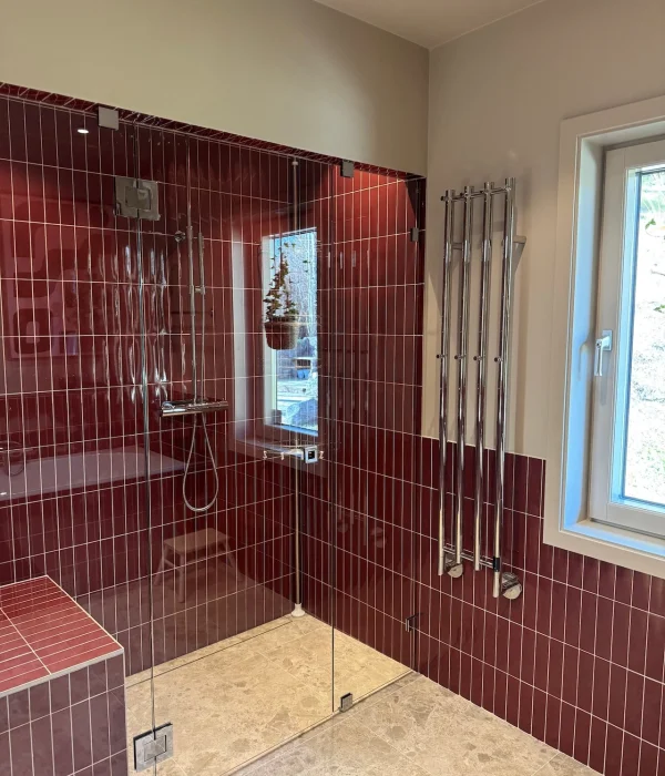 Badrumsrenovering i Stockholm med rött kakel i duschen med en handdukstork