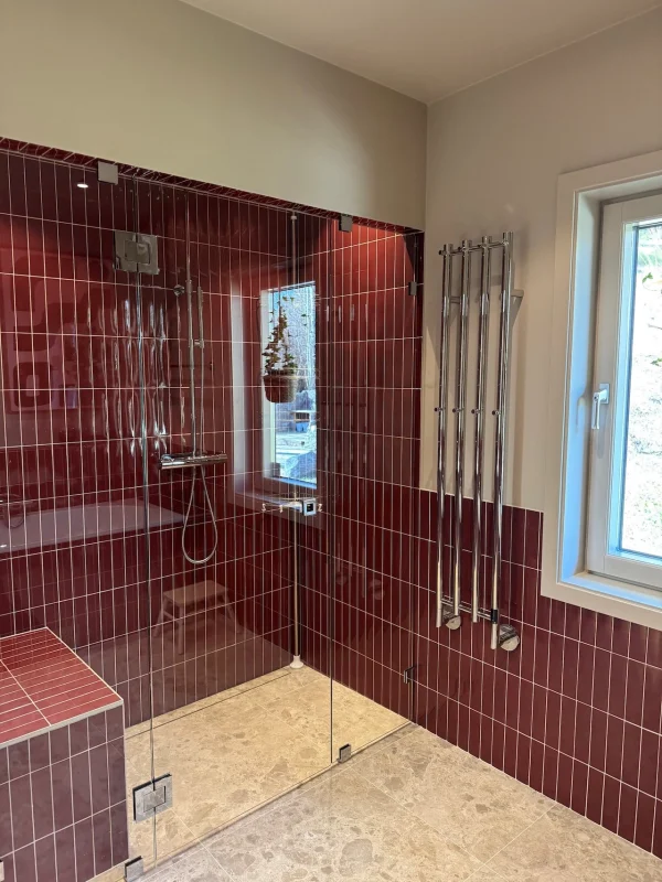 Badrumsrenovering i Stockholm med rött kakel i duschen med en handdukstork